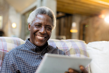 Portrait smiling, confident senior man using digital tablet on sofa