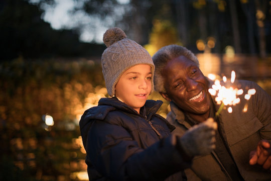 Grandfather and curious grandson playing with firework sparklers