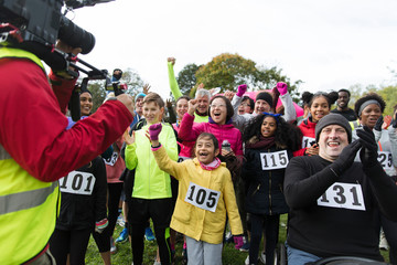 Cameraman filming cheering crowd of runners at charity race