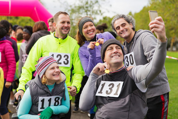 Friends with medals taking selfie at charity race in park