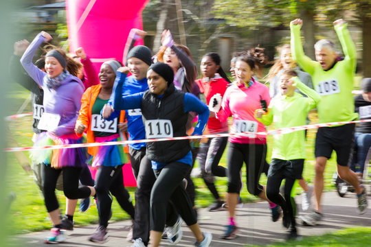 Enthusiastic runners cheering and running at charity run in park