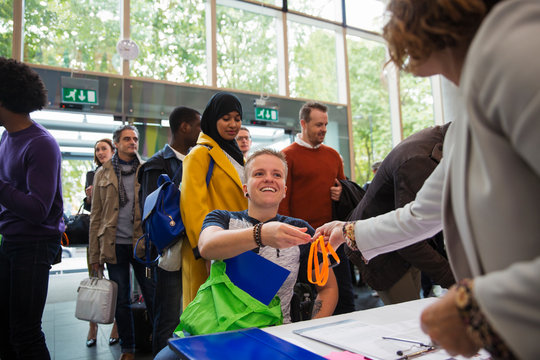 Smiling woman in wheelchair arriving checking in at conference registration table