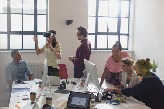 Computer programmers programming virtual reality simulator glasses in open plan office