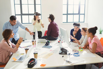 Computer programmers programming virtual reality simulator glasses in open plan office