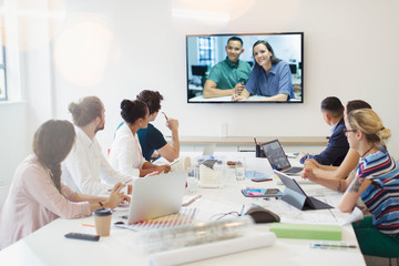 Designers video conferencing with colleagues in conference room meeting
