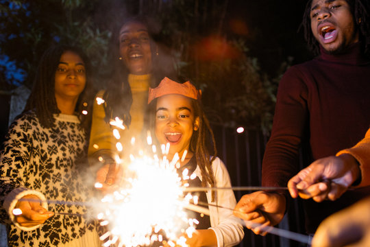 Playful girl with sparkler celebrating with family