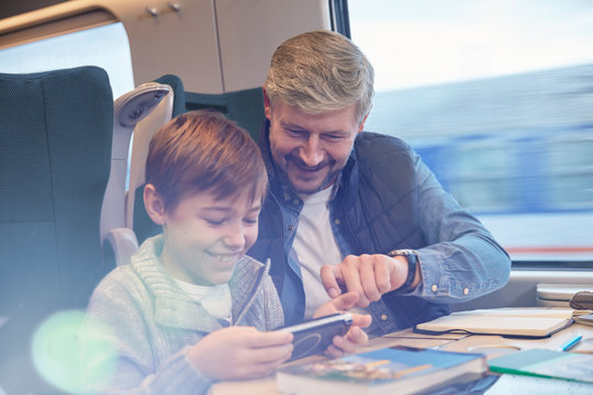 Father and son using smart phone on passenger train
