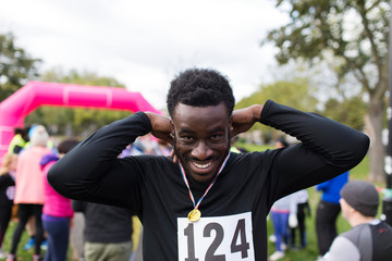 Portrait smiling, confident male runner wearing medal at charity run in park