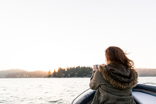 Woman using camera phone, photographing tranquil lake
