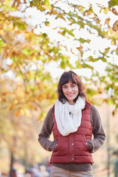 Portrait smiling woman in scarf and vest in autumn park