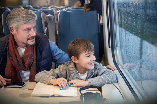 Father and son looking out window on passenger train