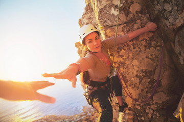 Female rock climber reaching for helping hand
