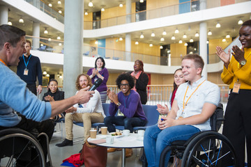 Colleagues clapping for speaker in wheelchair at conference