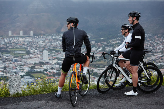 Male cyclist friends taking a break, looking at view from overlook