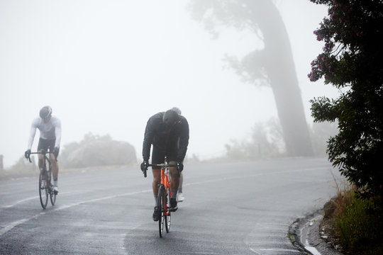 Dedicated male cyclists cycling on rainy road