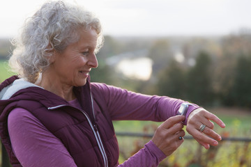 Active senior woman exercising, using fitness tracker smart watch