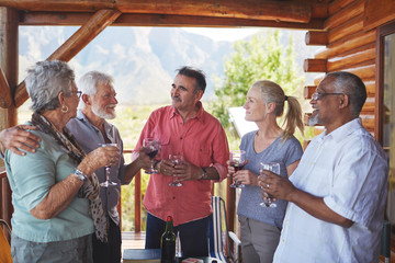 Active senior friends drinking wine on cabin balcony