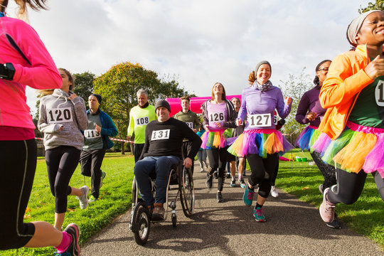 Man in wheelchair among runners at charity race in park