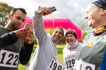 Happy runner friends taking selfie camera phone at charity run in park