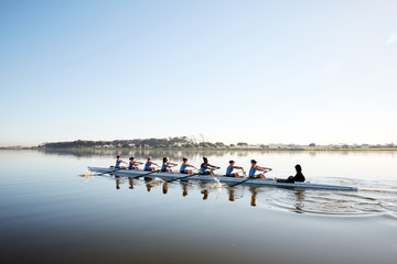 Female rowing team rowing scull on tranquil lake