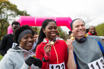 Portrait smiling runners with medals at charity run