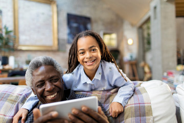 Portrait smiling grandfather and granddaughter with digital tablet