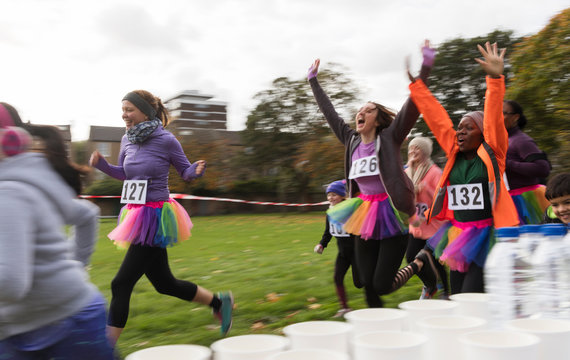 Enthusiastic female runners in tutus cheering, running at charity race in park