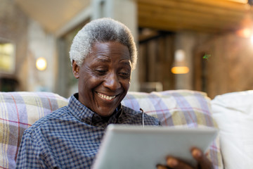 Smiling senior man using digital tablet on sofa