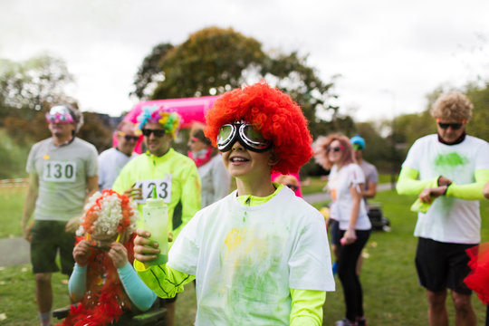 Playful boy runner in wig covered in holi powder at charity run in park