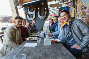 Portrait smiling friends eating at restaurant outdoor patio
