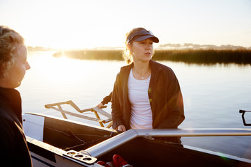 Focused female rower lifting scull at sunrise lakeside