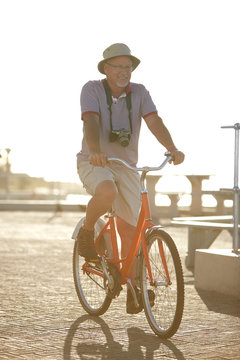 Active senior man tourist bike riding on sunny boardwalk