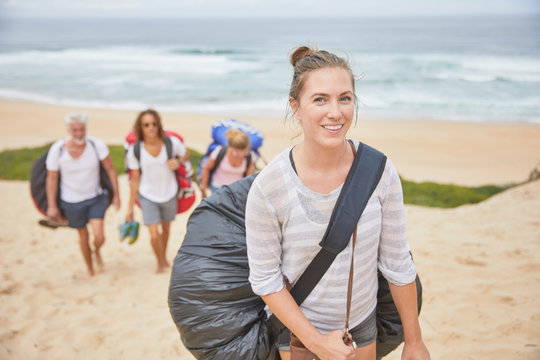 Portrait smiling, confident female paraglider carrying parachute backpack on beach