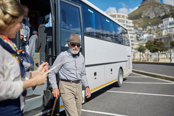 Active senior man tourist disembarking tour bus