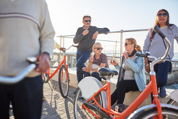 Active senior friend tourists with bicycles eating ice cream