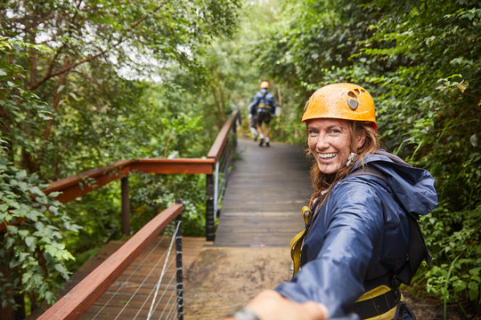 Portrait smiling woman zip lining in woods