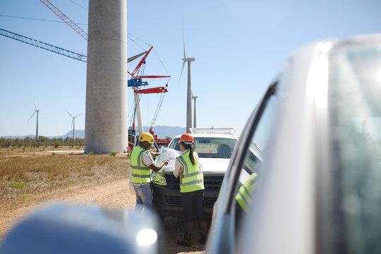 Engineers reviewing blueprints at wind turbine power plant