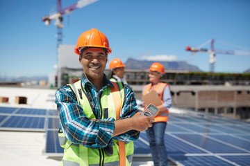 Portrait confident engineer installing solar panels on sunny rooftop