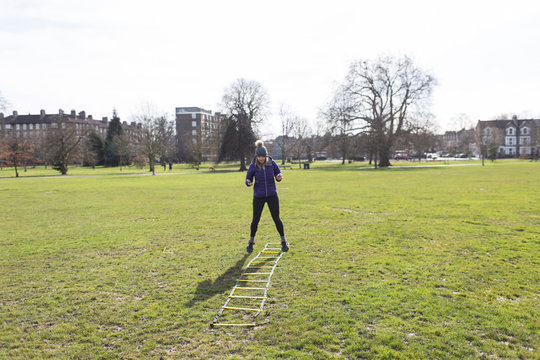 Woman exercising, doing speed ladder drill in sunny park