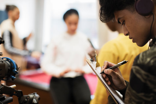 Focused teenage boy with clipboard vlogging