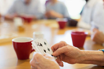 Close up senior woman playing cards with friends in community center