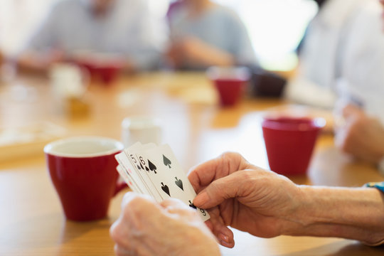 Close up senior woman playing cards with friends in community center