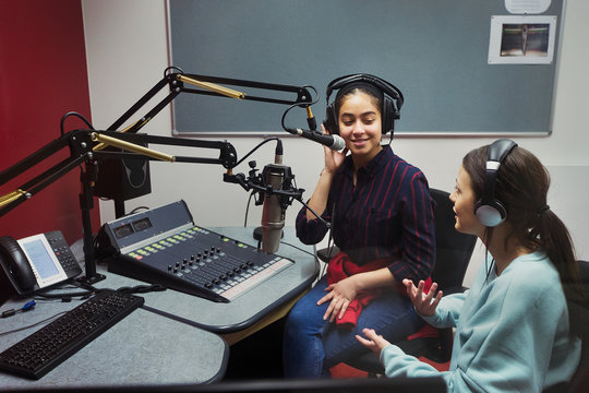 Teenage girl musicians recording music in sound booth