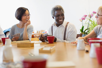 Senior friends playing games at table in community center