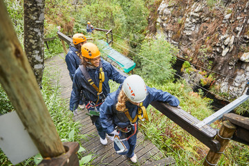 Friends walking on bridge, preparing to zip line