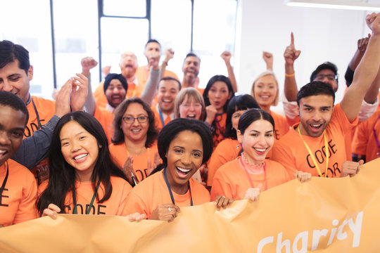 Happy hackers with banner cheering, coding for charity at hackathon