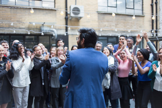Business people cheering for businessman in courtyard