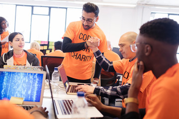 Hackers handshaking, celebrating and coding for charity at hackathon