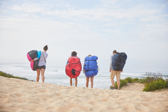 Paragliders carrying parachute backpacks on ocean beach