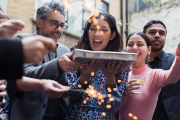 Friends celebrating with man holding birthday cake